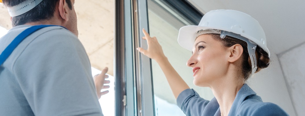 Architekt und Arbeiter auf Baustelle überprüfen die Fenster im Rohbau