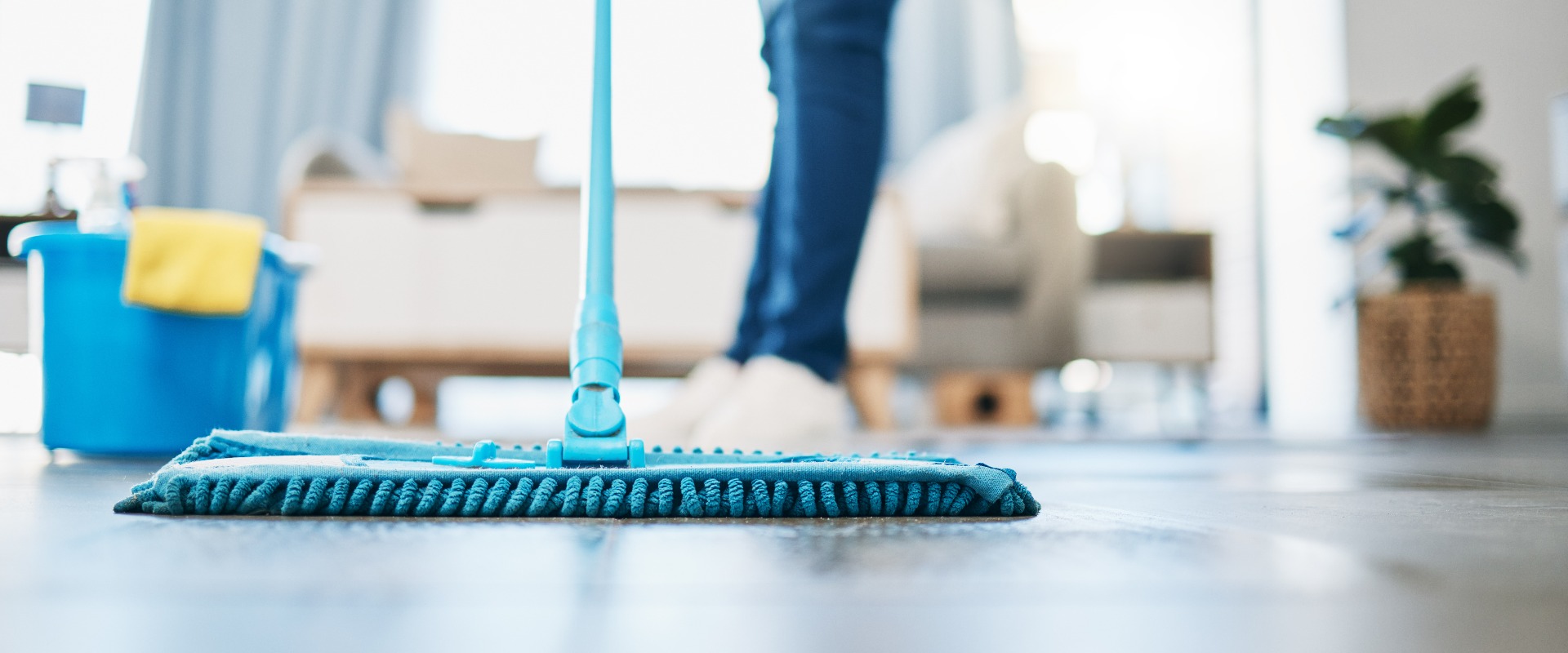 Housekeeping, cleaning and woman maid with a mop to clean the living room floor at a house. Female domestic worker, cleaner and housewife washing the ground for bacteria, dust or dirt in her home.