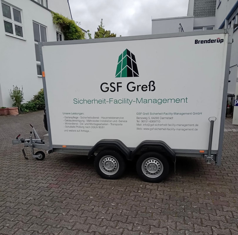 Ein weißer Anhänger mit dem Logo und Schriftzug von GSF Greß Sicherheit Facility Management steht auf einem gepflasterten Hof