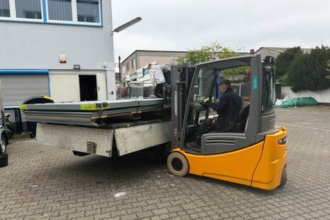 Ein konzentrierter Mann fährt einen gelben Gabelstapler und hebt eine schwere Last