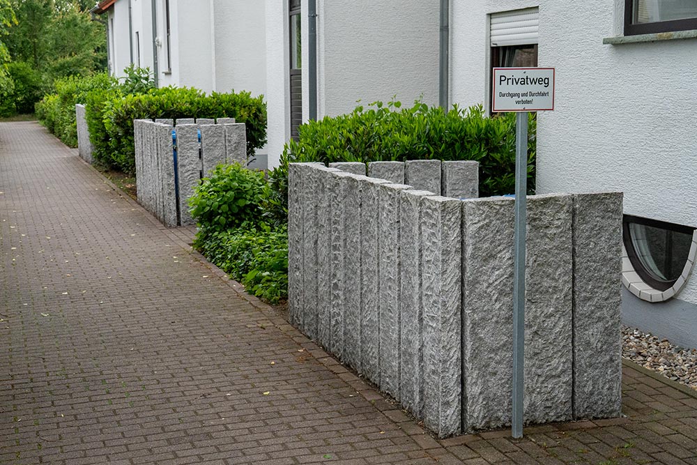 Grauer Gehweg neben Haus mit grünen Hecken und Privatweg Schild ohne Mimik