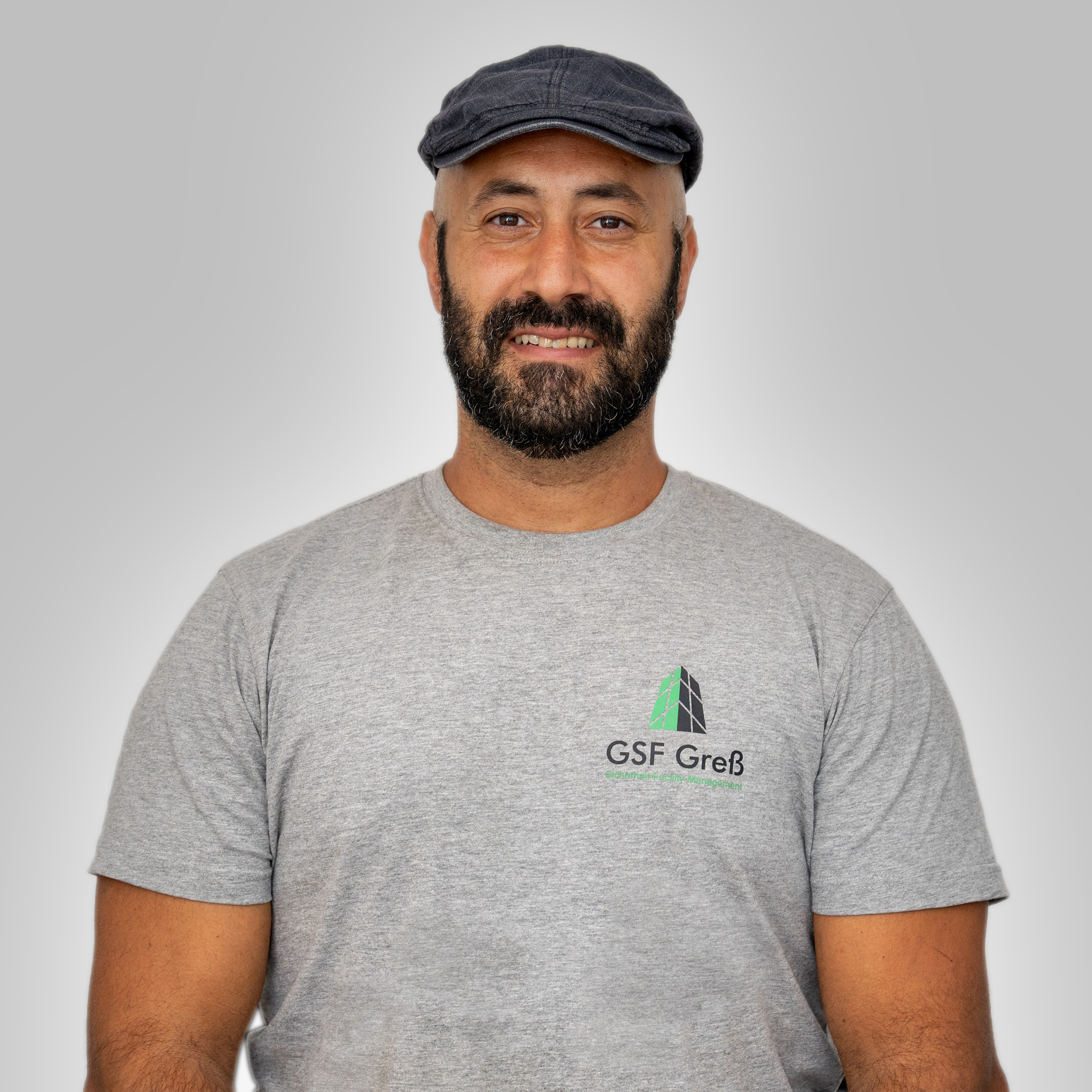 Laechelnder Mann mit Bart und dunkler Schirmmuetze im grauen GSF Gross Shirt